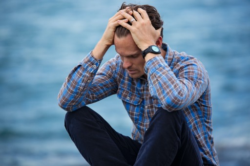 Man in blue and brown plaid shirt holding his head