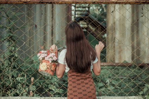 Young woman with flowers in basket near fence