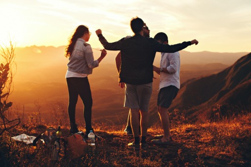 four people standing at top of a hill