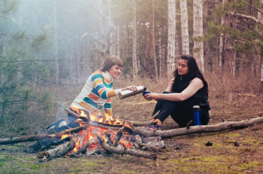 Two women sitting in front of a fire